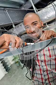 Man in roofspace holding roll cable and pliers