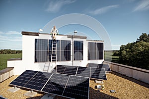 Man on rooftop of a private house with solar power station