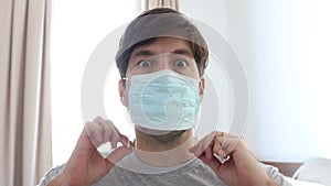 Man in a room putting a mask on his mouth, preventing disease