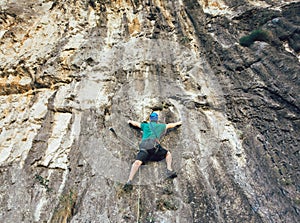 Man with a rope engaged in the sports of rock climbing