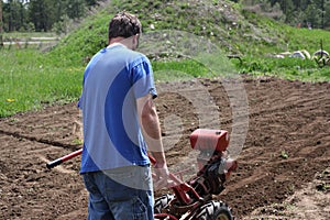 Man rototilling garden.