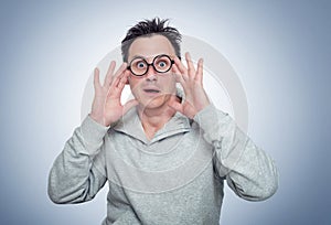 Man with round glasses in horror clutches his head, concept of emotion of deep fear