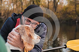 Man in a row boat kisses his dog.