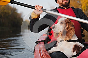 Man rowing a canoe with his spaniel dog, sunny autumn weather.