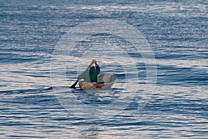 Man rowing his small boat in an open sea