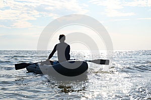 Man rowing inflatable rubber fishing boat on sea, back view. Space for text