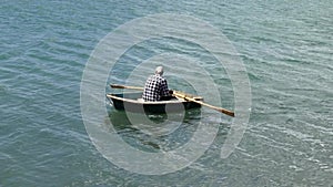 Man rowing a row boat at sea