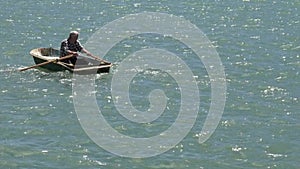 Man rowing a row boat at sea