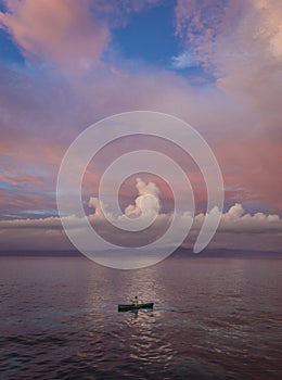 Man rowing a small canoe during sunset at Nusa Lembongan Island