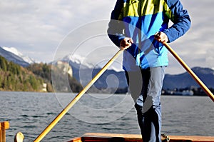 Man rowing on the typical wooden boat Pletna in the lake Bled, Slovenia, at sunset. Tourism, sport, exploring concept