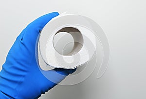 A man in rubber gloves holds a roll of toilet paper on a white background.Disinfection in public places, the fight against the vir