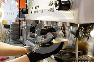 A man in rubber gloves makes delicious, natural coffee at a professional coffee machine close-up