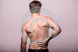 Man rubbing his painful back on grey . Pain relief, chiropractic concept