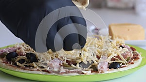 A man rubs cheese on a pizza. Cooking ingredients are laid out on it. Making pizza at home. Close-up shot