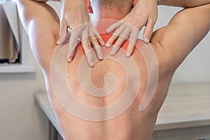 man rubs his hands with painful area in upper back. man suffering from neck and shoulder pain