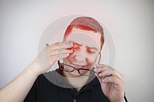 A man rubs his tired eyes with his hands on a white background. The concept of eye fatigue from the computer and fatigue from work