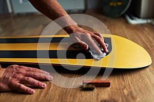 Man rubs snowboard sponge wax on wooden floor