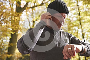 Man On Run Checking Activity Tracker And Putting In Earphones