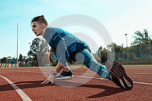 Man runner stretching legs preparing for run training on stadium tracks doing warm-up