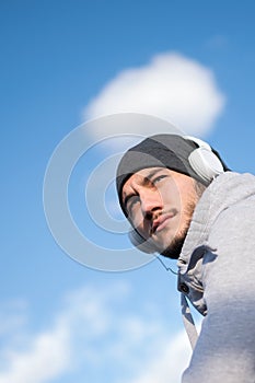Man runner taking a break after intensive training outdoors, listening music on his mobile smart phone