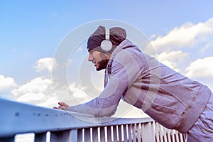 Man runner taking a break after intensive training outdoors, listening music on his mobile smart phone