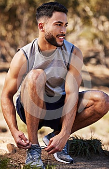 Man, runner and tying laces in nature, prepare and ready for exercise or outdoor fitness. Male person, athlete and