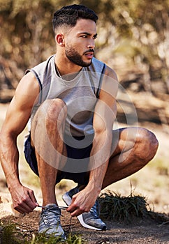 Man, runner and tying laces in outdoors, prepare and ready for workout or nature fitness. Male person, athlete and
