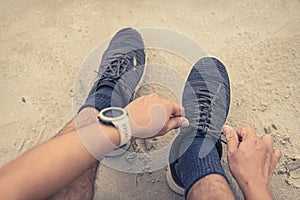 Man runner tying shoelace ready to run on beach