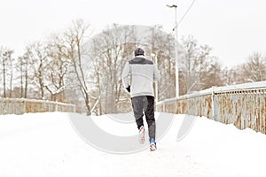 Man running along snow covered winter bridge road
