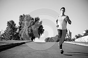 Man running on asphalt road on sunny summer day