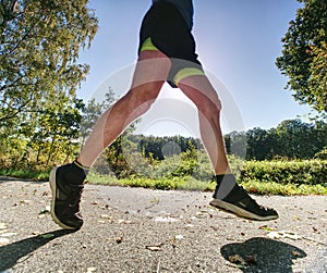 Man running on asphalt track. Athlete running fast in a park