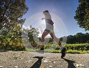 Man running on asphalt track. Athlete running fast in a park