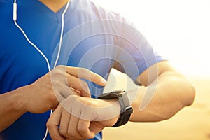 Man running on beach and checking Heart Rate Monitor On watch