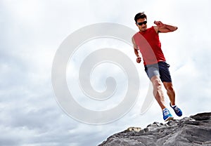 Man, running and beach for fitness, health and wellness in activewear and sunglasses. Athlete male person, jog and