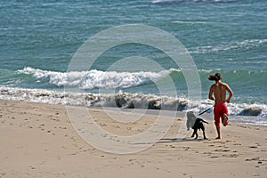 Man running with dog in the beach