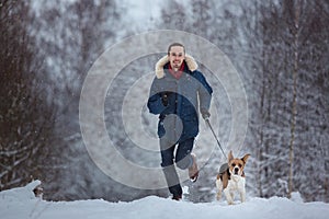 Man running with dog beagle in winter. Snowing day