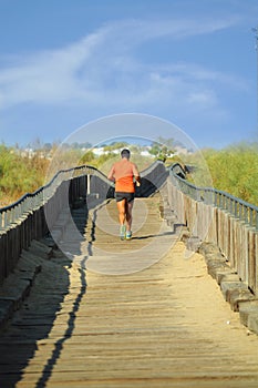 Man running at the morning on woodden path