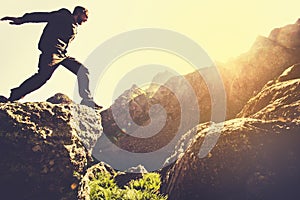 Man running on Mountains jumping cliff over lake