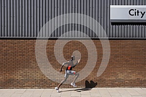 Man Running Past Brick Wall With 'City' Written On It