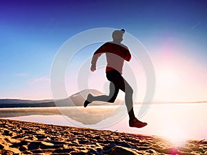Man running at seaside twilight time. Runner athlete running at seaside. Sportsman fitness silhouette