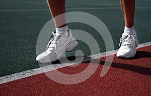A man in running shoes stands at the stadium at the start line. the athlete is preparing for the competition. legs in sneakers clo