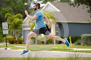 Man running on street in neighborhood. Handsome athlete running in the street. Full length shot of man in sportswear