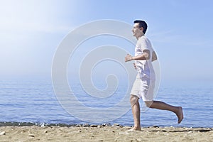 Man running on sunny beach. Unrecognizable body jogging on ocean beach. Running on tropical beach. Attractive man enjoying nature.