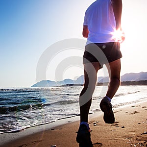 Man running at sunset on a sandy beach in a sunny day