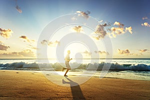 Man running on tropical beach at sunset