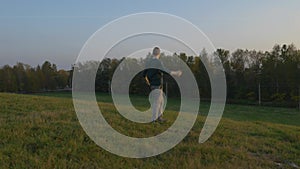 A man runs down a hill, throws off his backpack.