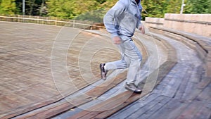 Man runs down and then up a set of stairs in the park. Man jogging the stairs in park.