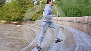 Man runs down and then up a set of stairs in the park. Man jogging the stairs in park.