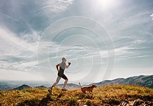 Man runs with his beagle dog on mountain top