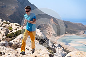 Man runs on a rocks against a blue sea